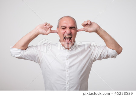 Mature european man closing his ears because of loud sound and noise. I do not want listen to you. 45258589