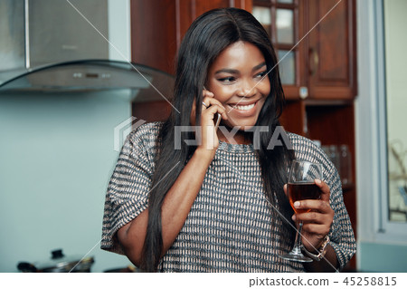 Smiling woman with wineglass speaking on phone 45258815