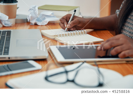 Crop businesswoman with tablet writing in notepad 45258816