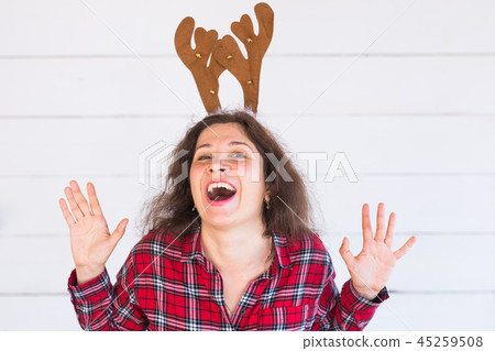 People, holidays and christmas concept - funny cheerful santa girl in deer horns on her head on 45259508