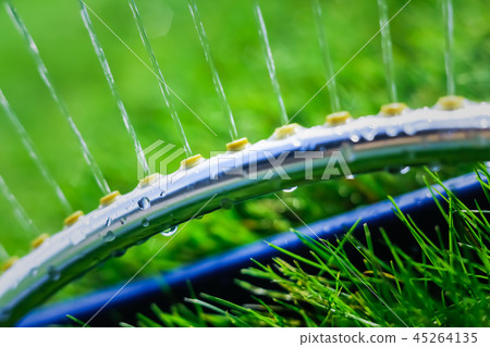 Lawn sprinkler spaying water over green grass Lawn sprinkler spaying water over green grass 45264135