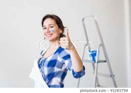 Repair, renovation and people concept - young woman painting the wall and looks like very happy, she Repair, renovation and people concept - young woman painting the wall and looks like very happy, she 45265799