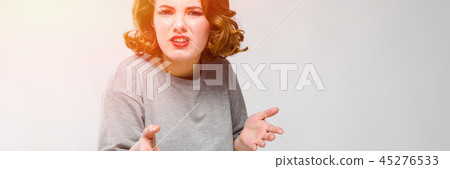 Charming young girl in a gray T-shirt on a gray background. The girl spread her arms 45276533