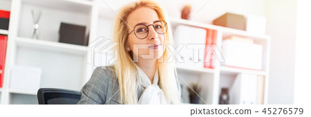 A young girl in glasses works in the office with a marker, a notebook and documents. A young girl in glasses works in the office with a marker, a notebook and documents. 45276579