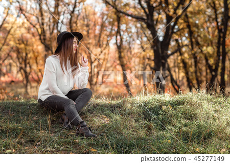 beautiful woman sitting on grass on sunny autumn day. beautiful woman sitting on grass on sunny autumn day. 45277149