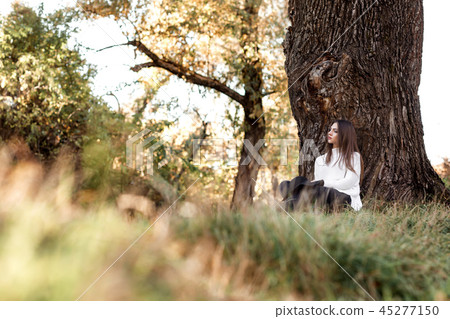 beautiful woman in black hat sitting under big tree beautiful woman in black hat sitting under big tree 45277150