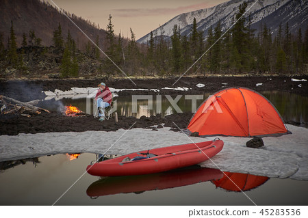 View of camp life in a mountain terrain. Lake shore with canoe View of camp life in a mountain terrain. Lake shore with canoe 45283536