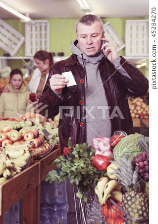 Man specifying shopping list in store Man specifying shopping list in store 45284270