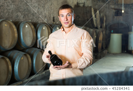 man with bottle of wine in winery cellar. man with bottle of wine in winery cellar. 45284341