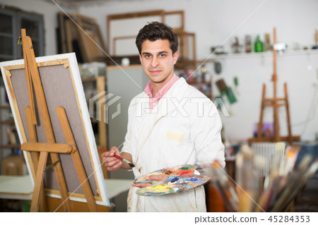 Man near easel painting on canvas 45284353