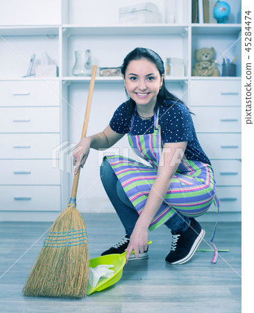Young mistress sweeping floors 45284474