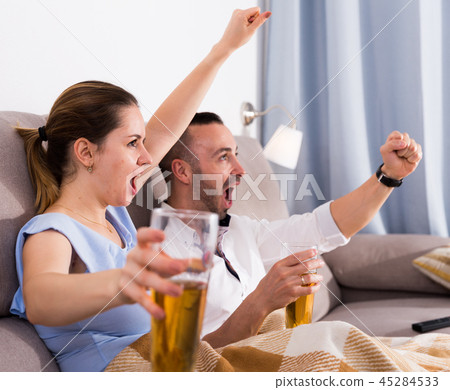 Young female and her husband are faning in time watching football 45284533