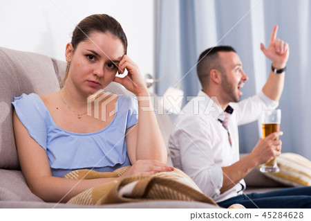 Sad female is sitting alone when her husband is watching TV 45284628