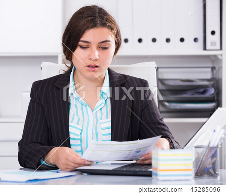 Office manager woman is reading documents about the transaction 45285096