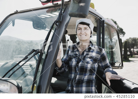 Confident female farm owner driving tractor 45285110