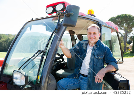positive adult farmer is sitting on the car at the cowfarm 45285232