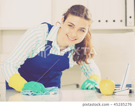 Female cleaner is cleaning dust from the desk Female cleaner is cleaning dust from the desk 45285276