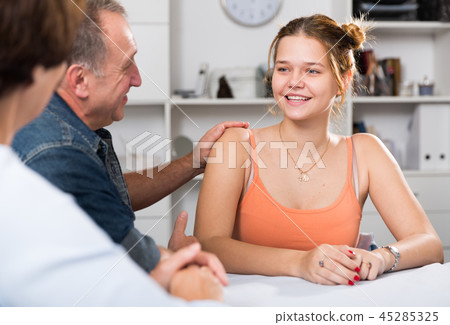Smiling woman is talking with her parents at the table 45285325