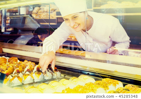 Portrait of baker with sweet cakes in local confectionery Portrait of baker with sweet cakes in local confectionery 45285348