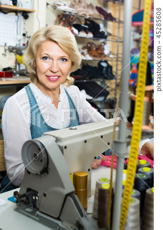 happy mature woman tailor using sewing machine happy mature woman tailor using sewing machine 45285608