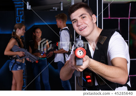 Excited guy with laser pistol while playing lasertag with his friends Excited guy with laser pistol while playing lasertag with his friends 45285640