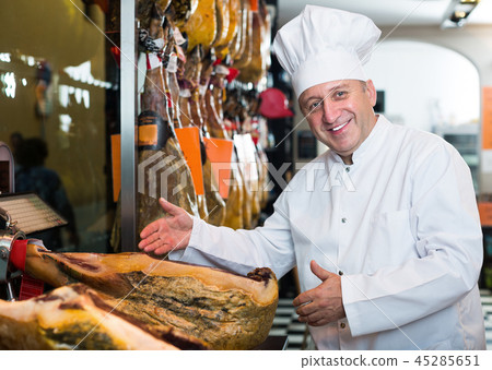 Elderly man seller showing Spanish jamon Elderly man seller showing Spanish jamon 45285651