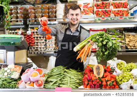 friendly man seller showing assortment of grocery shop 45285858