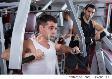Guy training on fitness machine in gym 45285914