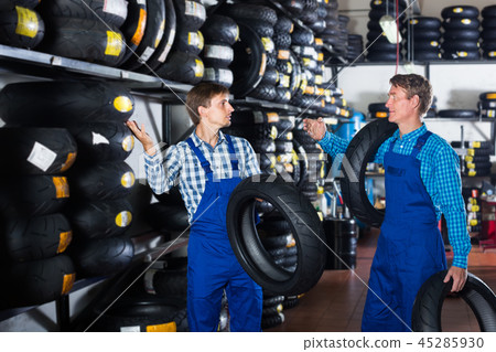 Two polite colleagues working with motorcycle tires Two polite colleagues working with motorcycle tires 45285930