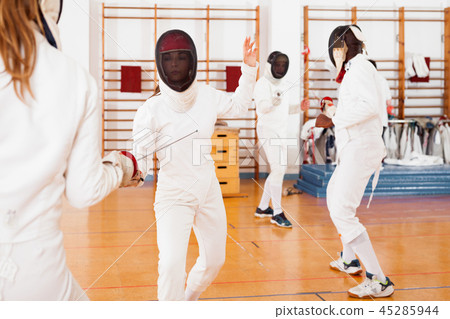 Two female fencers exercising movements in duel at fencing room 45285944