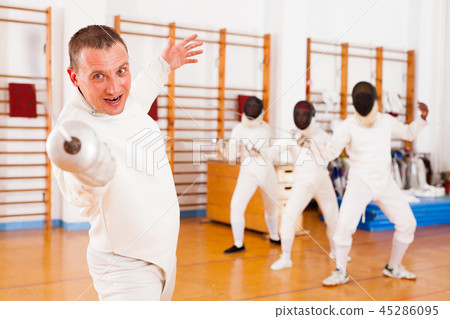 Sporty young man fencer practicing effective fencing techniques 45286095