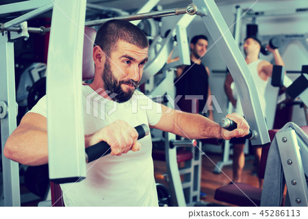 Guy training on fitness machine in gym Guy training on fitness machine in gym 45286113