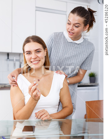 Happy young girlfriends looking betrothal ring and chatting at table 45286120