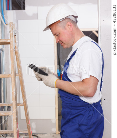 Smiling workman using phone Smiling workman using phone 45286133
