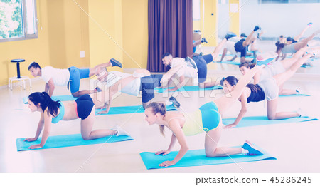 Young positive people stretching in dance hall Young positive people stretching in dance hall 45286245