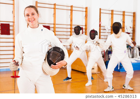Smiling young female in uniform standing at fencing room Smiling young female in uniform standing at fencing room 45286313