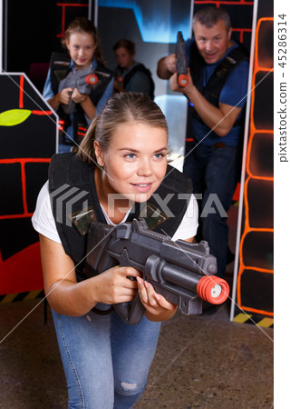 Young woman holding laser gun and playing lasertag game with family Young woman holding laser gun and playing lasertag game with family 45286314