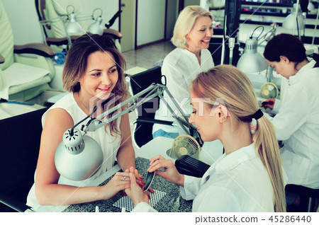Two women clients having manicure done in nail salon 45286440