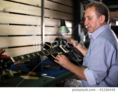 Adult guitarist is repairing his guitar Adult guitarist is repairing his guitar 45286449