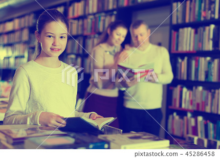 Portrait of intelligent preteen girl browsing textbooks in public library Portrait of intelligent preteen girl browsing textbooks in public library 45286458