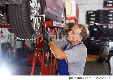 Mechanic installing car wheel after repair of balancing 45286583