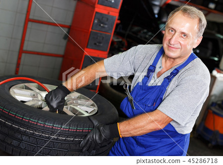 Professional car mechanician inflating tyre Professional car mechanician inflating tyre 45286718