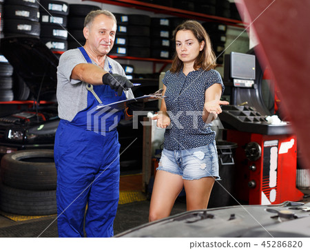 mechanic standing with client, writing job sheet for repairs mechanic standing with client, writing job sheet for repairs 45286820