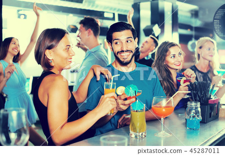 adult satisfied male with female are talking and drinking cocktails on the party 45287011