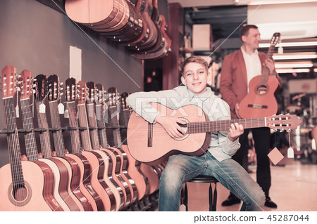 Male seller showing guitar to boy client 45287044