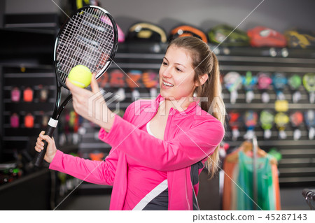 Adult woman is choosing tennis rocket and ball Adult woman is choosing tennis rocket and ball 45287143