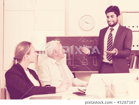 Office manager male is reading financial report to colleagues on meeting Office manager male is reading financial report to colleagues on meeting 45287167