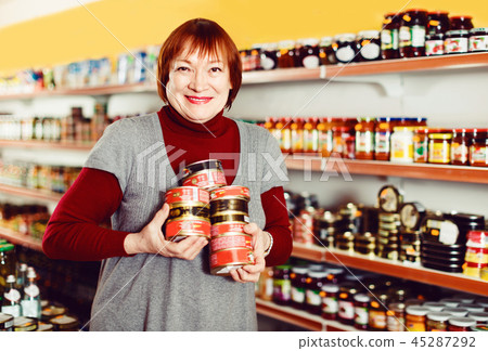 woman buyer choosing canned fish food in tin at the supermarket 45287292