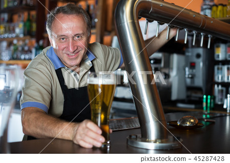 Smiling barman is offering unbottled beer to next client 45287428