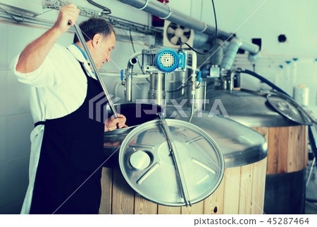 Brewer is controls the brewing process near reservoir with beer Brewer is controls the brewing process near reservoir with beer 45287464
